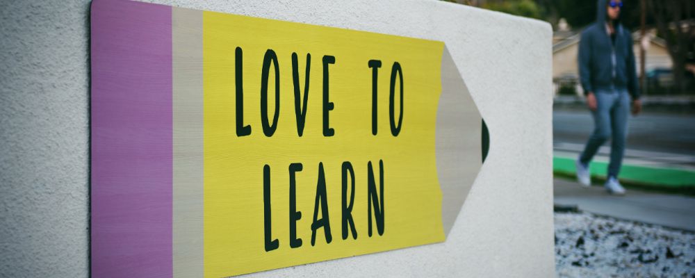 Brisbane education copywriter walks past a sign that says 'love to learn'.