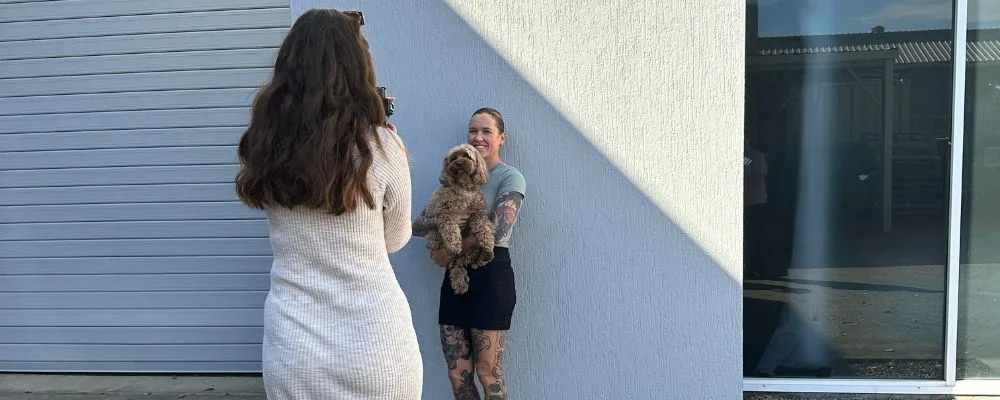 Caitlin taking photos of a woman holding a dog. The dog is being an absolute diva. 