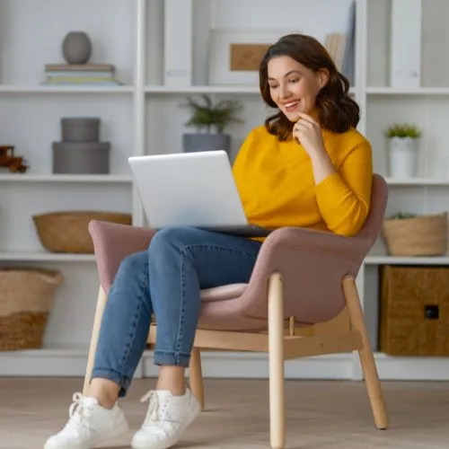 Woman sits on chair with laptop learning about Keyword intent in SEO Campaigns.